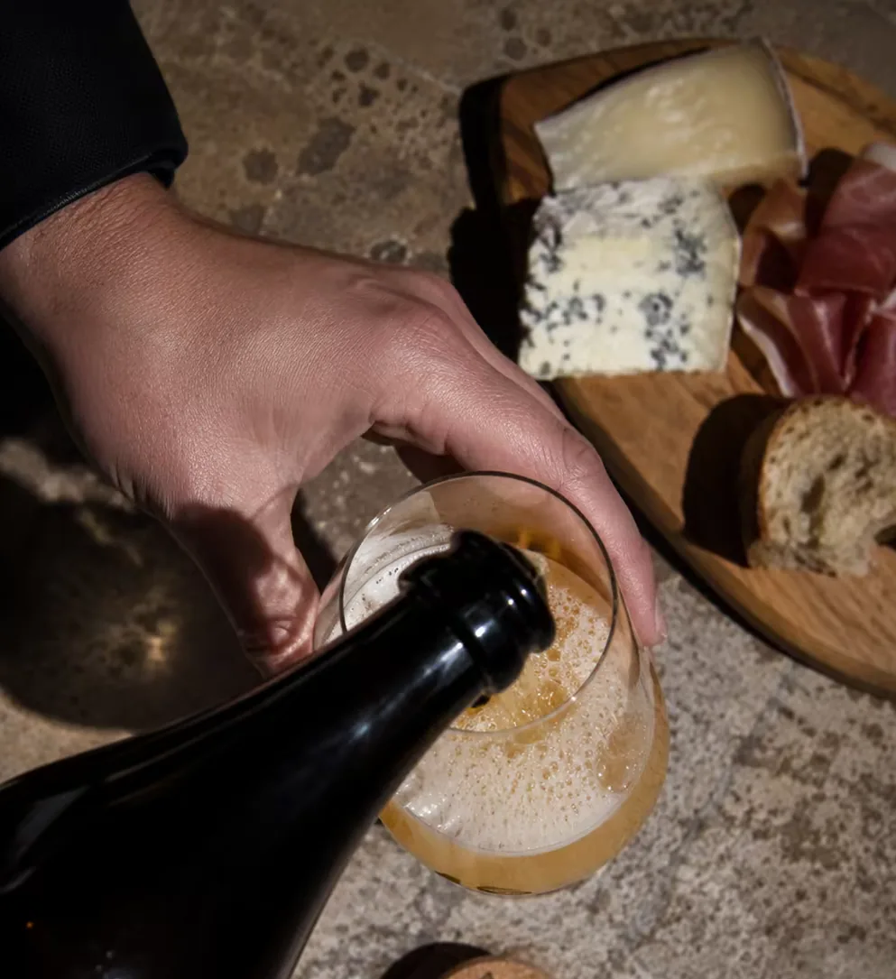 Fiá versata in un calice accanto a un tagliere di formaggi e salumi